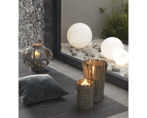 Dekorativní scéna s lucernou, polštářem, větrnými světly z větví a zahradními koulemi na štěrku