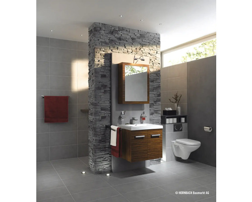 Koupelna s umyvadlem, zrcadlem, toaletou a obkladem stěn s kamenným vzhledem