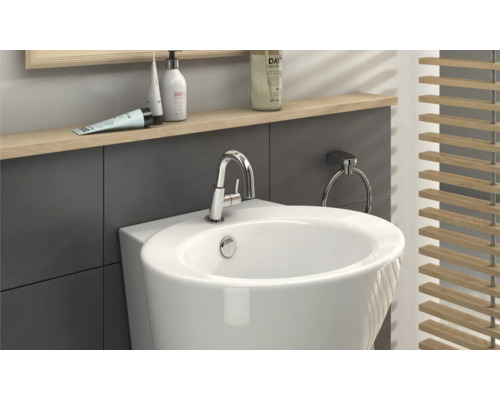 Detailní pohled na koupelnu s bílým umyvadlem, baterií, kroužkem na ručníky a dřevěnou žaluzií