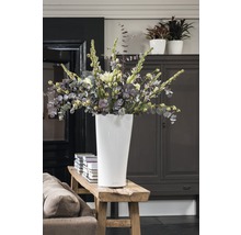 Vysoká bílá váza s kyticí na dřevěné lavici v pokoji