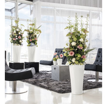 Světlý interiér s květinovou výzdobou ve vysokých květináčích, křeslech a koberci