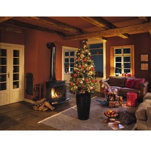 Vánoční obývací pokoj s krbem, pohovkou a ozdobeným vánočním stromkem v květináči.