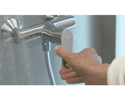Ruka ovládá sprchovou armaturu pro koupelnu