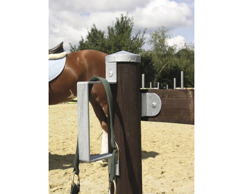 Detailní záběr dřevěného sloupku s držákem a jezdeckými potřebami