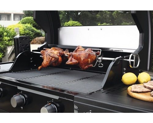 Plynový gril se dvěma pečenými kuřaty na otočném rožni a citrony na dřevěné desce