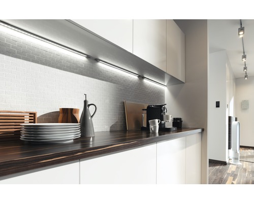 Moderní kuchyně s pracovní deskou, nádobím, kávovarem a podsvícením