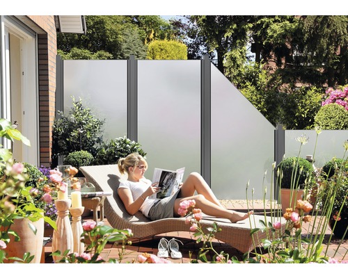 Terasa s prvky na ochranu soukromí, zahradním nábytkem a ženou na lehátku