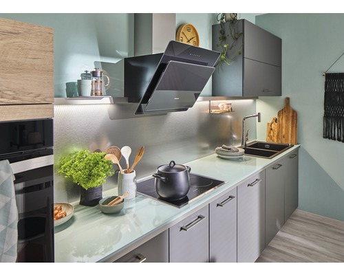 Světlá kuchyně s digestoří, dřezem a varnou deskou.