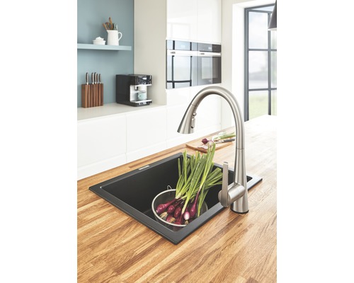 Kuchyňský dřez s baterií a zeleninou na dřevěné pracovní desce