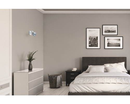 Ložnice s postelí, komodou, nočním stolkem, nástěnnou lampou a zarámovanými obrazy