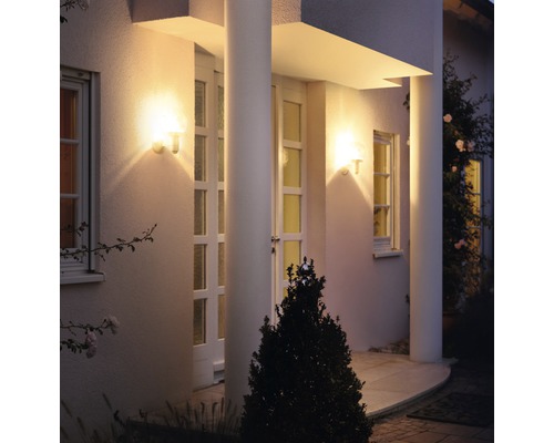 Osvětlená fasáda domu se dvěma venkovními světly vedle vchodových dveří.