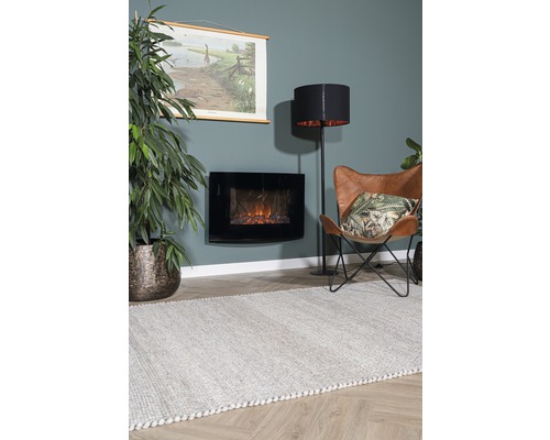 Obývací pokoj s černým elektrickým krbem, stojací lampou, křeslem a kobercem.