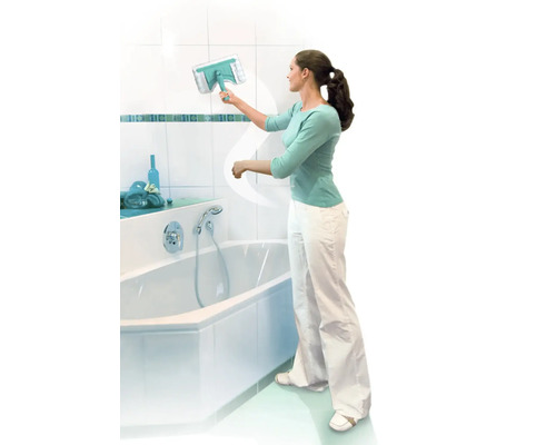 Žena čistí obkladačky v koupelně stěrkou na okna vedle vany