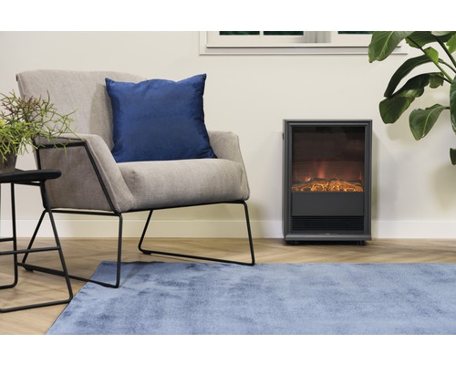 Obývací pokoj s křeslem, ozdobným polštářem, odkládacím stolkem, pokojovou rostlinou, kobercem a elektrickým krbem