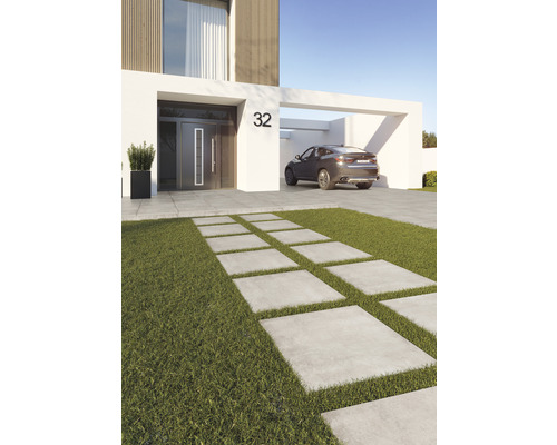 Pohled na moderní dům s cestou z betonových desek skrz trávník a auto v přístřešku pro auto
