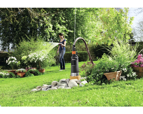 Zahrada s hlubinným čerpadlem a ženou zalévající rostliny