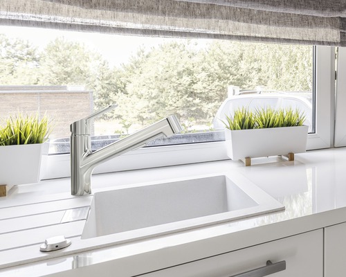 Kuchyňský dřez s vodovodní baterií na kuchyňské lince před oknem