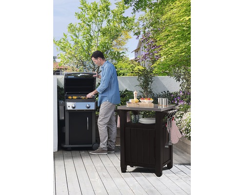 Scéna s mužem u grilu a grilovacím stolem na zahradě