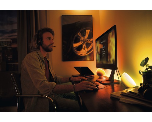 Scéna muže se sluchátky před počítačem, osvětleného dvěma stolními lampami