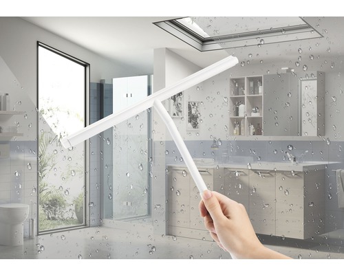 Osoba čistí sprchový kout stěrkou v koupelně