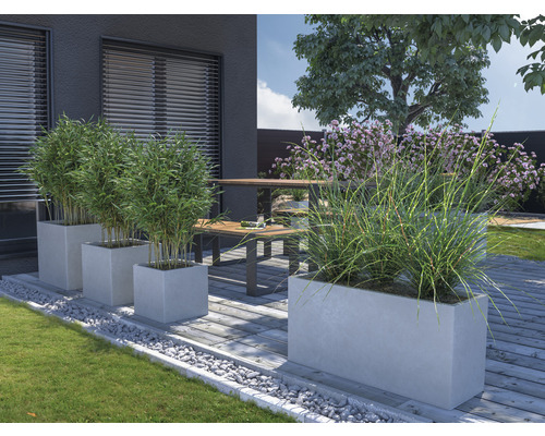 Zahradní prostor s betonovými květináči, rostlinami a posezením na terase
