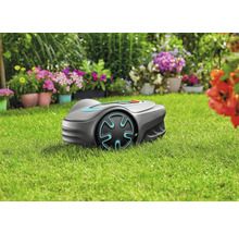 Robotická sekačka na trávníku před květinovými záhony