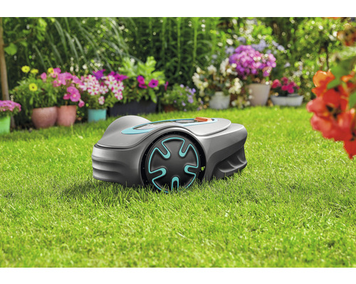 Robotická sekačka na trávníku před květinovými záhony
