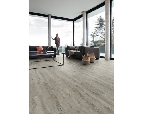 Světlý obývací pokoj s velkým oknem, pohovkami, stolem a světlou dřevěnou podlahou