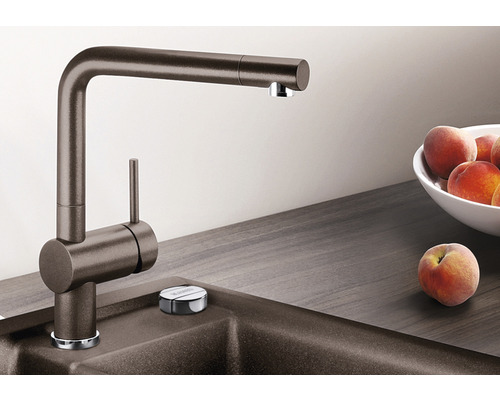 Kuchyňská baterie z kovu vedle dřezu a ovoce