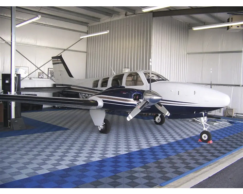 Letadlo v hangáru s podlahovými dlaždicemi.