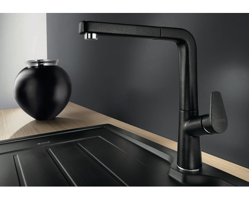 Černá kuchyňská baterie s výsuvnou sprchou vedle dřezu a dekorace