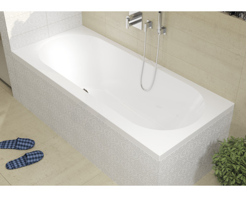 Bílá vana s armaturou a obloženým předkem v koupelně.