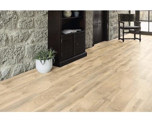 Světlá dřevěná podlaha v místnosti s kamennou zdí, tmavou dřevěnou skříní a židlí