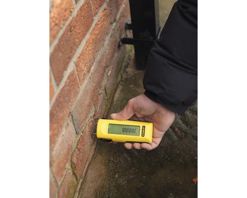 Měřič vlhkosti používaný na cihlové zdi