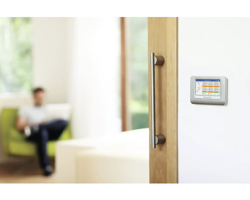 Scéna obývacího pokoje s digitálním termostatem na zdi.