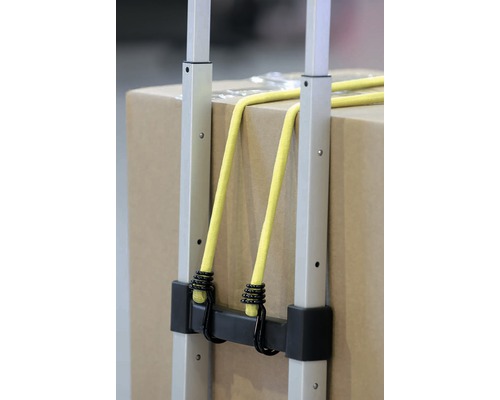 Detailní pohled na transportní vozík s popruhy a kartonovou krabicí.