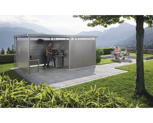 Zastřešené grilovací místo s mužem grilujícím a rodinou v pozadí