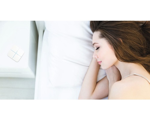 Žena spí v posteli s vypínačem chytré domácnosti na nočním stolku