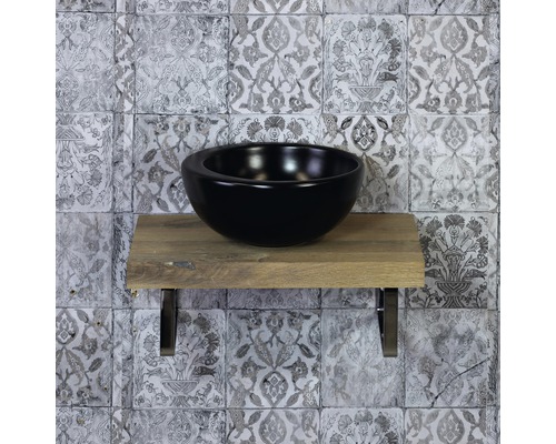 Černé umyvadlo na desce z dřeva s obklady na stěně v pozadí