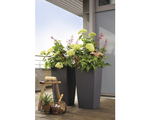 Dva vysoké květináče s květinami a rostlinami na dřevěné podlaze.