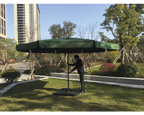 Čtvercový zahradní slunečník s osobou upravující velikost na zahradě.