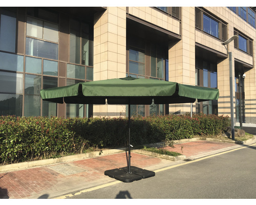 Zahradní slunečník s křížovou základnou na terase před budovou.