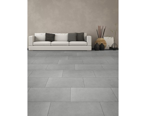 Světlý obývací pokoj s dlaždicemi, pohovkou a dekoracemi.