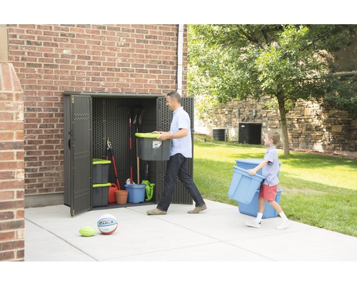 Scéna s plastovou zahradní skříní se dvěma dospělými ukládajícími zahradní nářadí