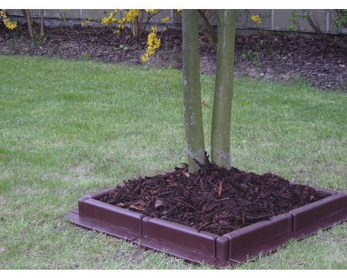 Plastový okrasný lem stromu s mulčovací kůrou na zahradě.