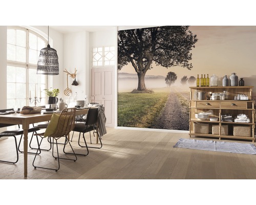 Jídelna s dřevěným stolem, židlemi, lampou a nástěnnou malbou s motivem krajiny.