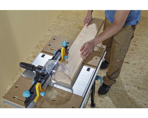 Osoba obsluhuje pracovní stůl s dřevěnou deskou.