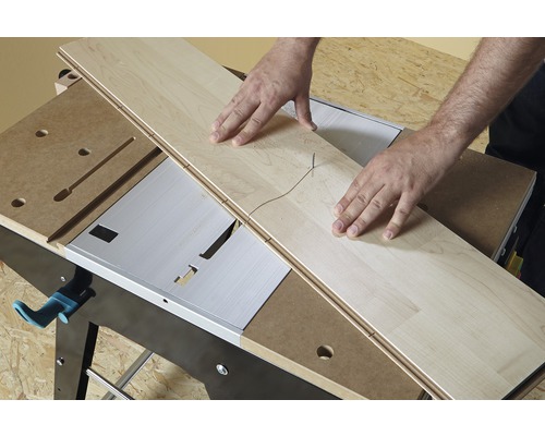 Osoba řeže laminátovou desku stolní pilou.