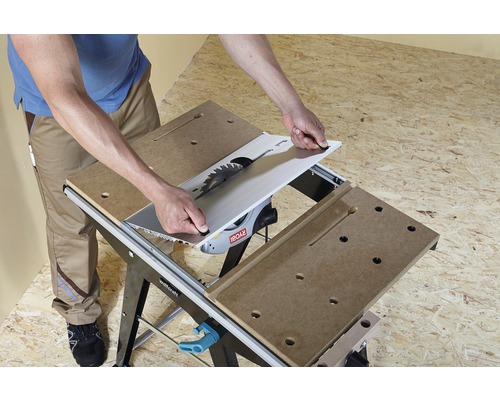 Muž montuje stolní pilu na pracovní stůl.