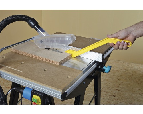 Stolní pila s dřevem a rukou držící posuvnou tyč